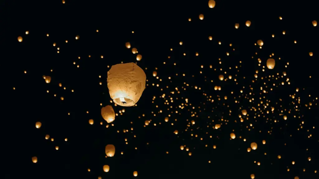 A sky filled with glowing paper lanterns against a dark night backdrop. The lanterns float upwards, creating a serene and enchanting atmosphere.
